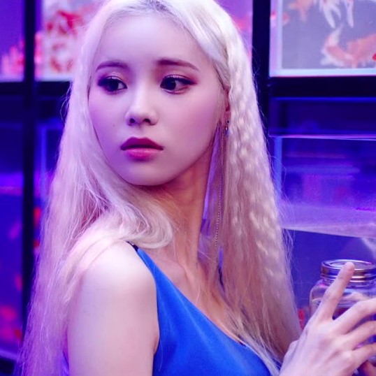 Jinsoul from the 'Singing in the Rain' music video. She has long blonde hair and is wearing a blue dress. She is holding a jar with a fish inside.